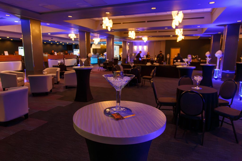 Spacious event venue interior with round tables and ambient lighting.