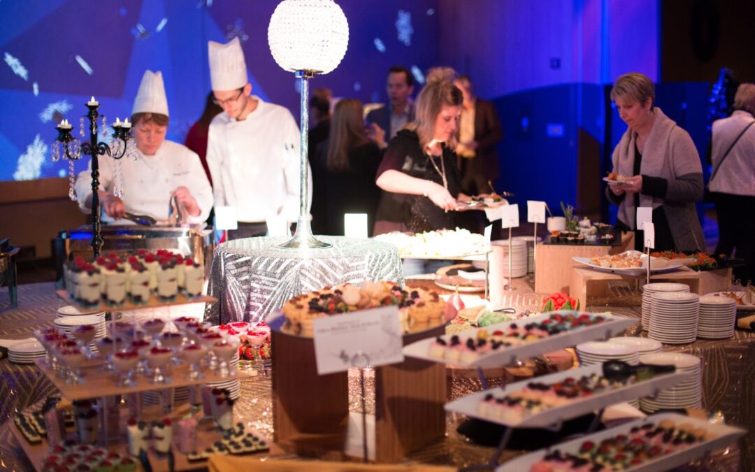 A group of attendees and caterers mill around an hors d’oeuvres table.